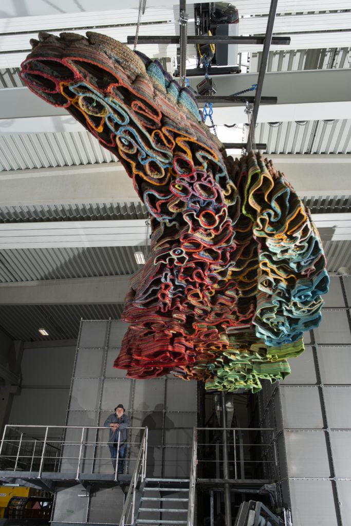 finished 3d printed artwork hanging of roof in factory while artis proudly looking at it