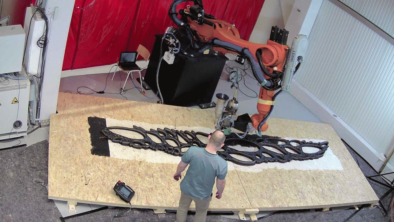 worker taking care of robot printing large sculpture in factory