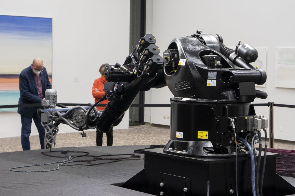 robot prints sculpture in museum while visitors are watching