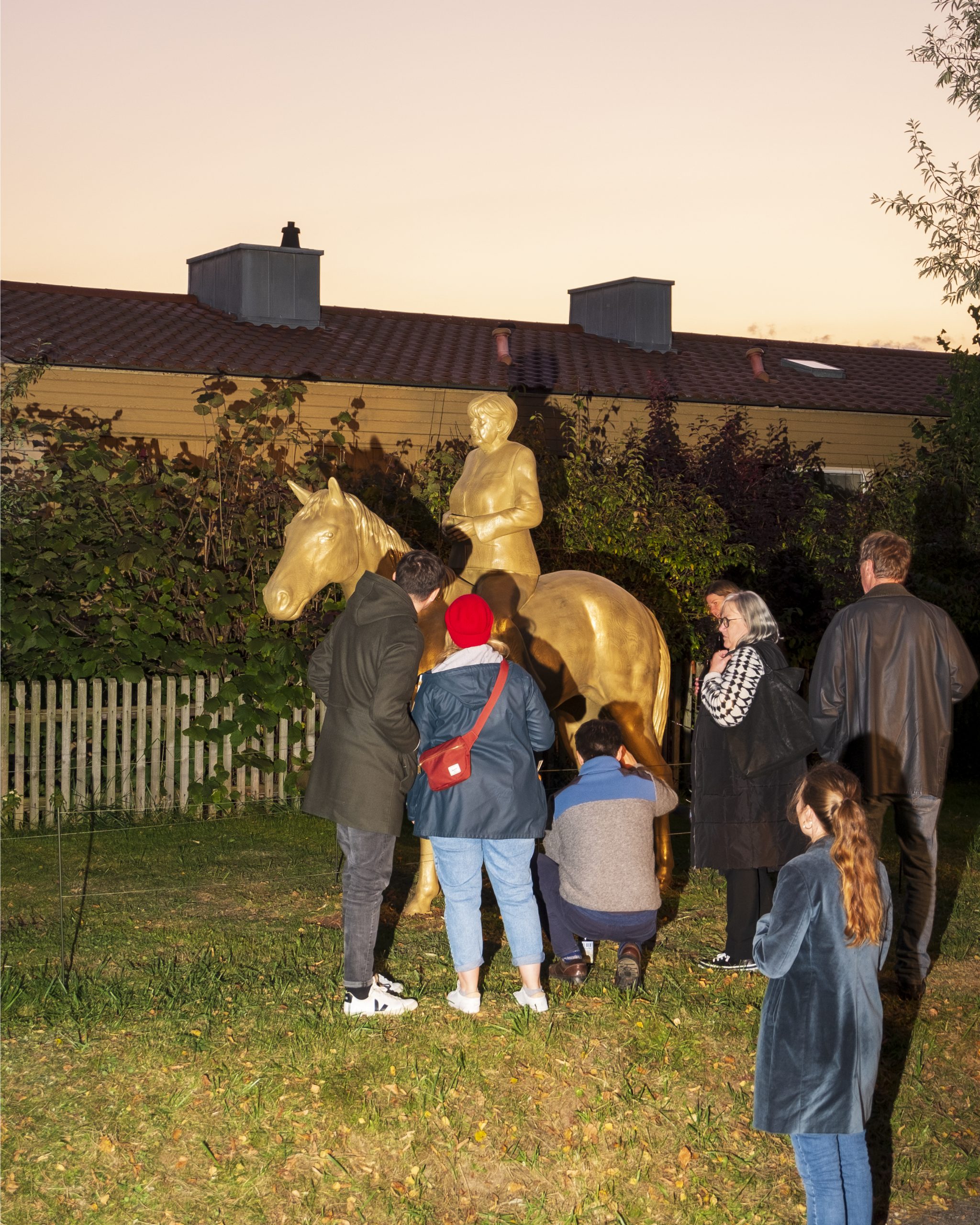 Golden equestrian Statue of Angela Merkel with surrounding visitors